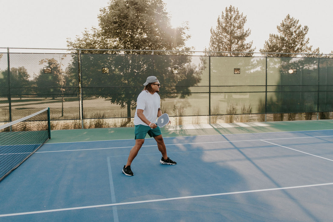 man holds pickleball paddle on outdoor pickleball court near salt lake city, UT