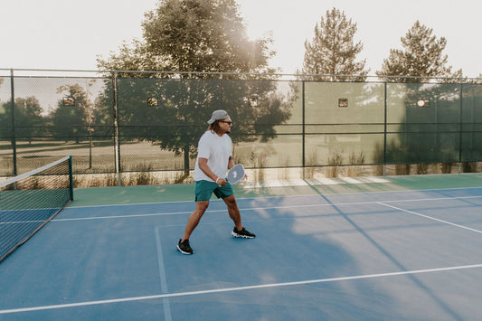 man holds pickleball paddle on outdoor pickleball court near salt lake city, UT