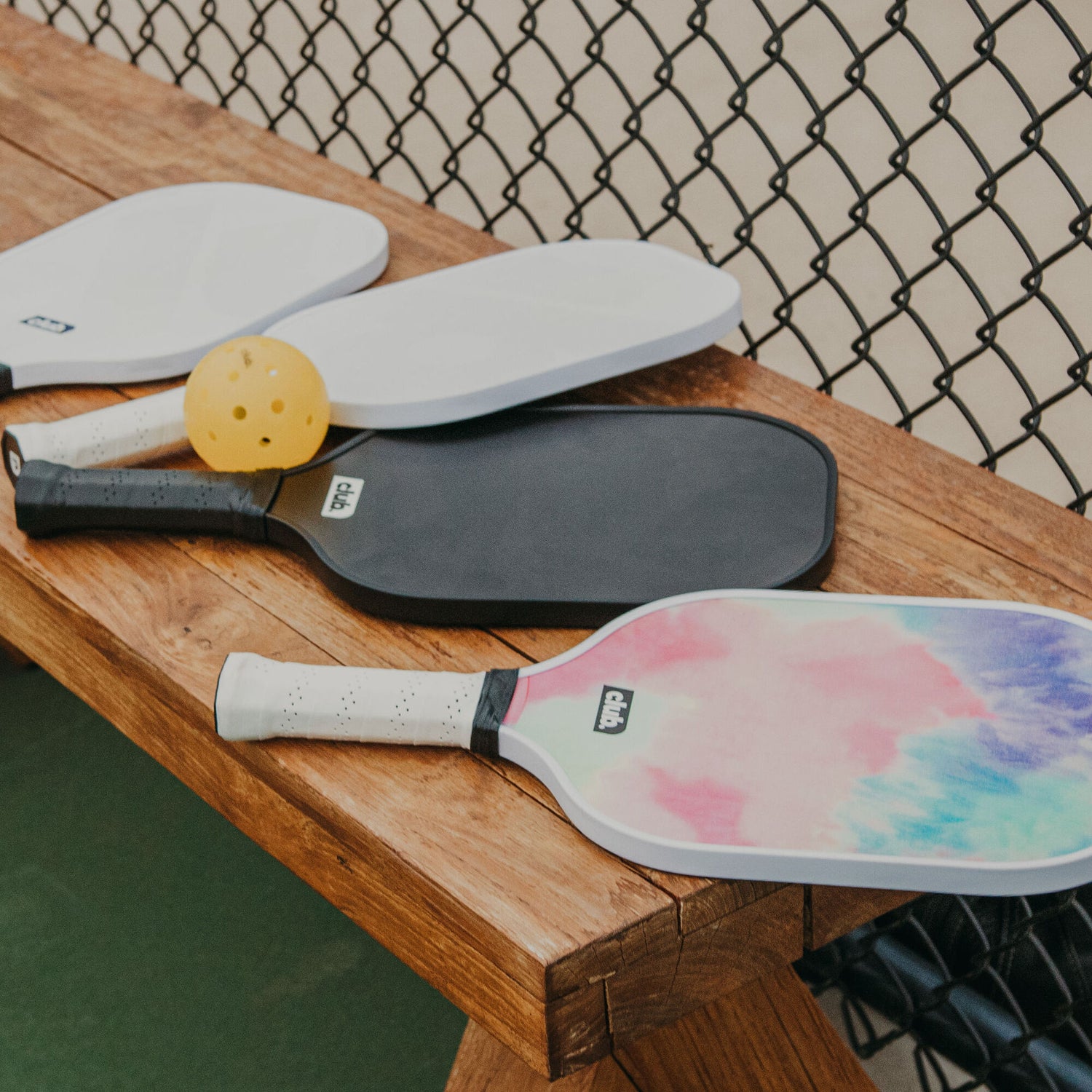 tie dye & black & white pickleball paddles on a bench